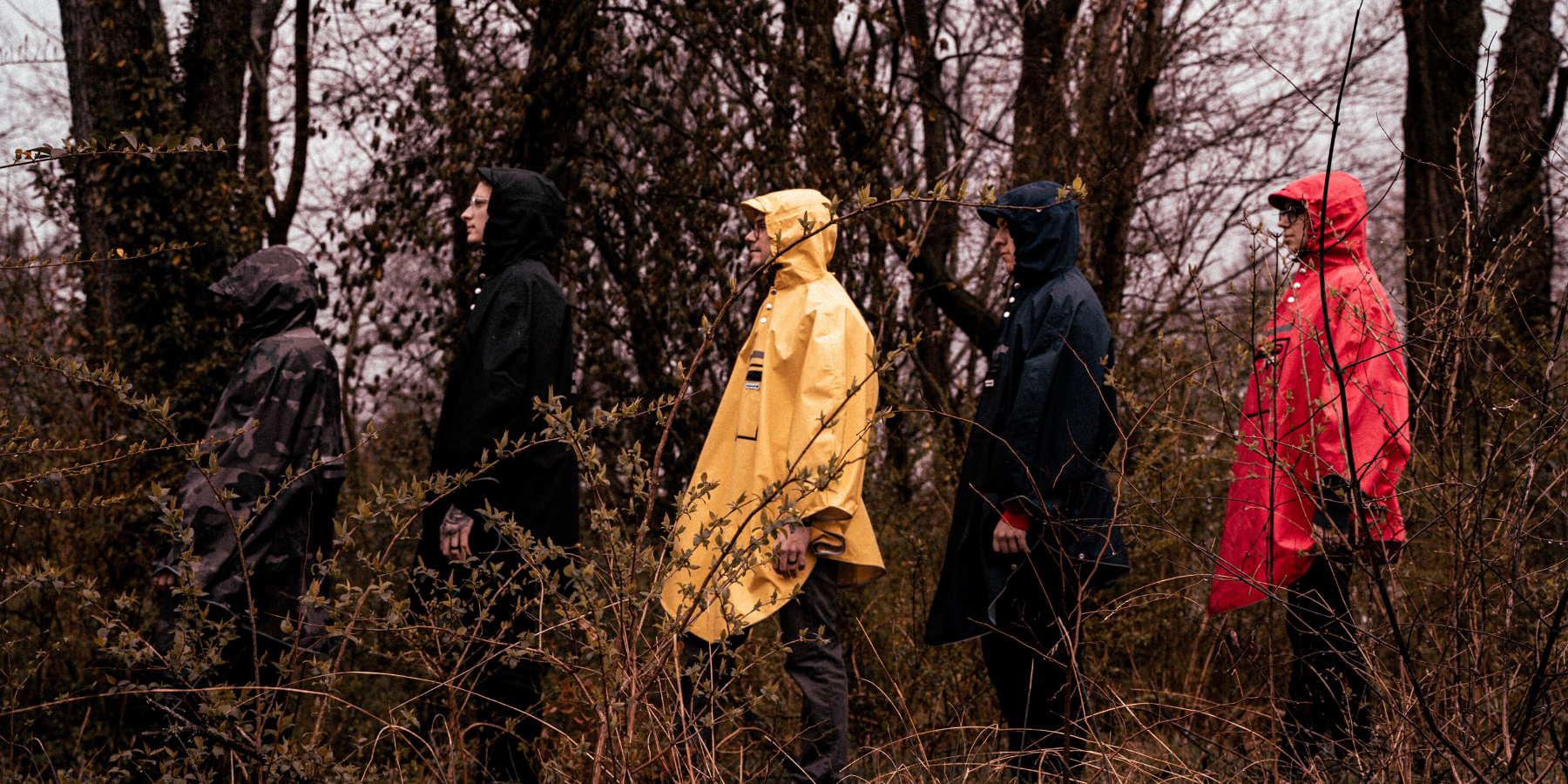Group of people wearing the people's poncho rainwear in all colours including: red, black, navy, yellow and camo