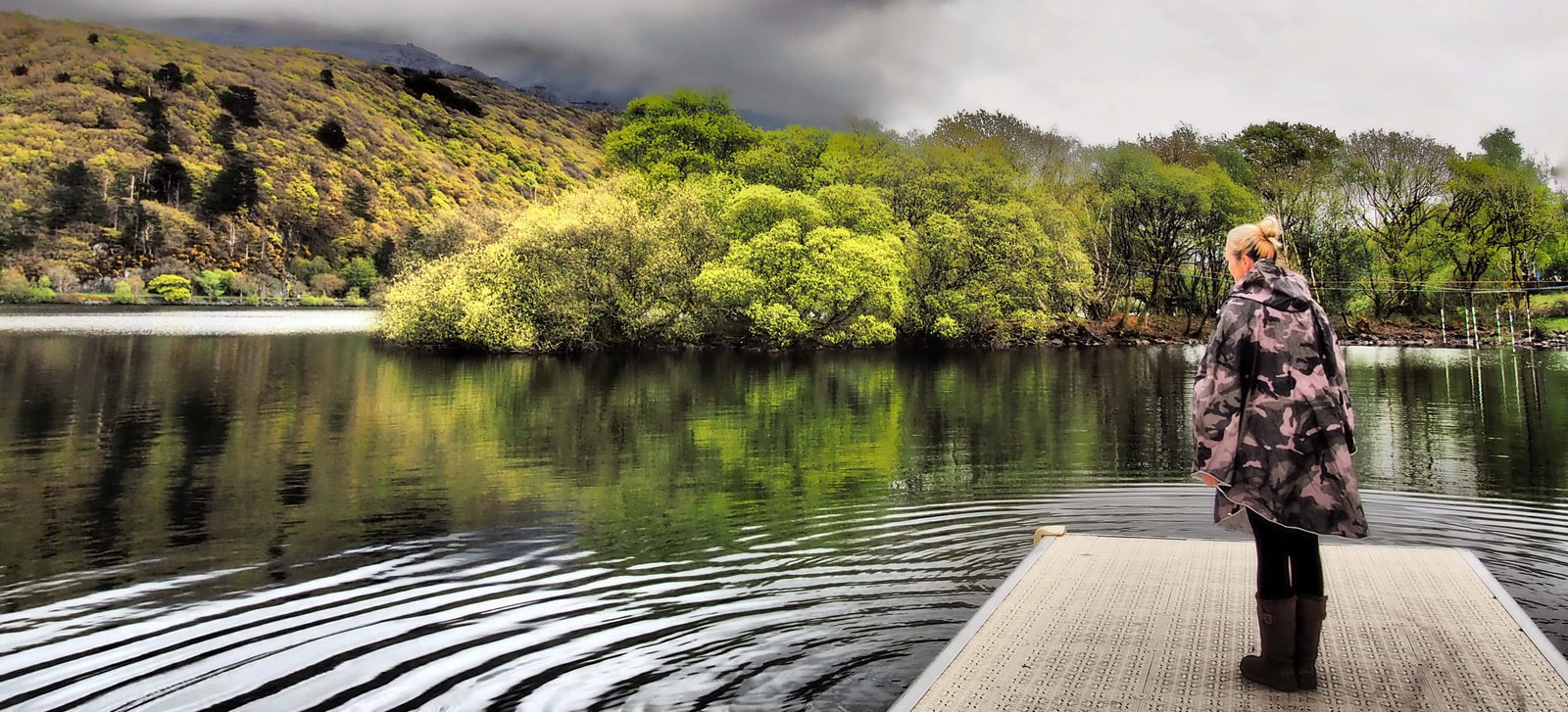Person standing by the water while wearing a waterproof poncho by the people's in camo